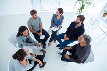 Un grupo de personas están sentadas en círculo hablando entre sí.