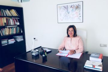Una mujer está sentada en un escritorio frente a una estantería.
