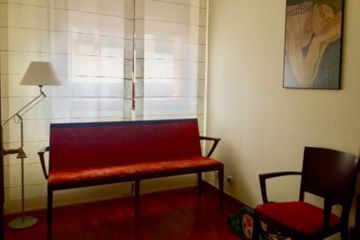 Una sala de espera con un banco rojo y dos sillas