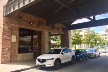 Un coche blanco está aparcado bajo una marquesina delante de un edificio.