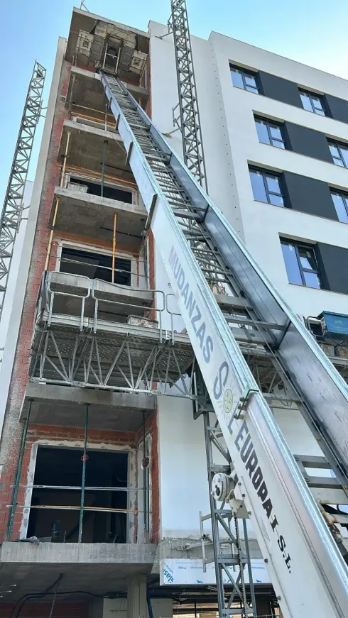 Edificio en construcción con ascensor extensible, el cielo está despejado.
