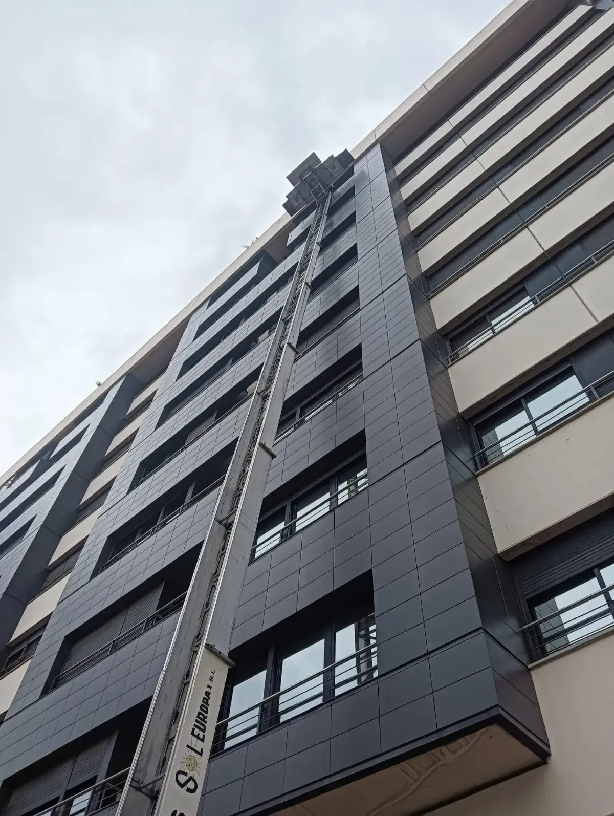 Plataforma elevada que llega a un edificio alto, posiblemente para mover objetos.