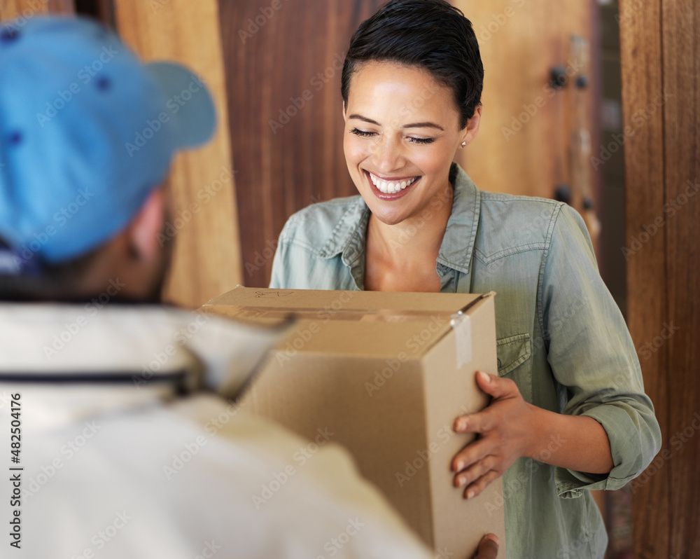 Eine Frau lächelt, während sie ein Paket von einem Lieferboten entgegennimmt.