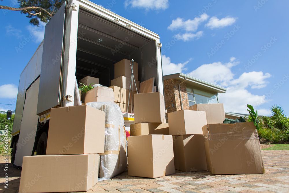 Ein Umzugswagen voller Kartons steht vor einem Haus.