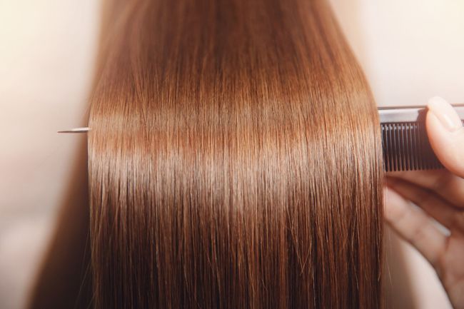 Una mujer se peina su largo cabello castaño con un peine.