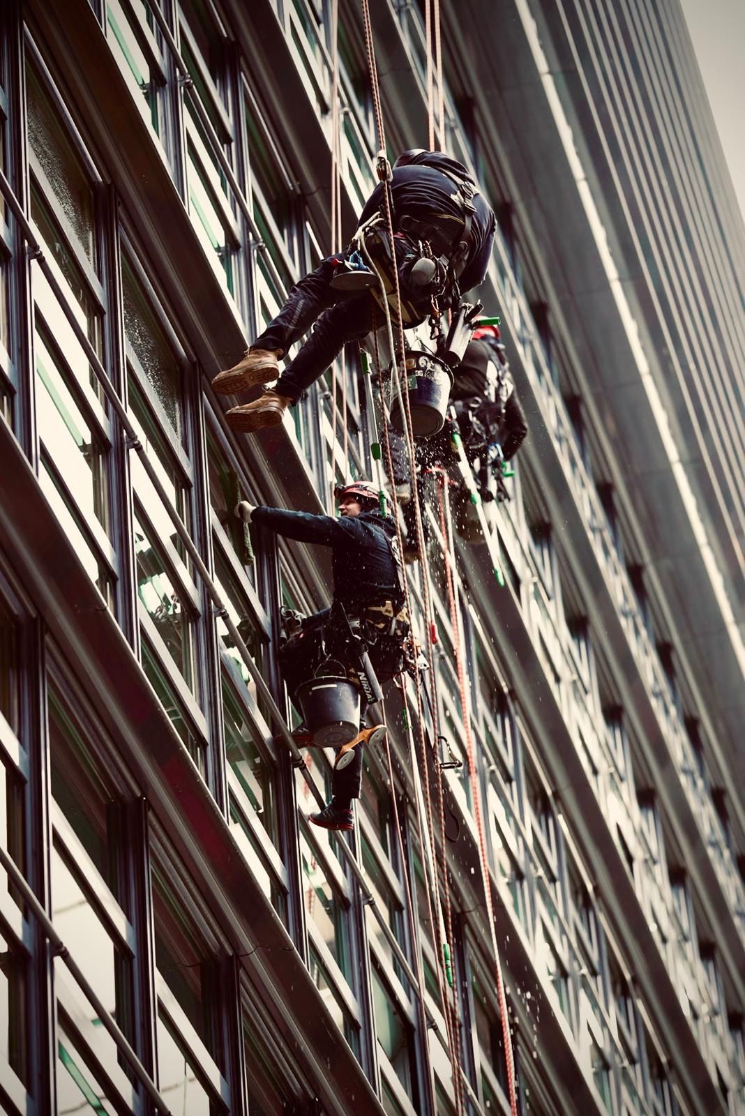 Cleanclimb: Mitarbeiter klettert an der Seite eines Gebäudes hoch.