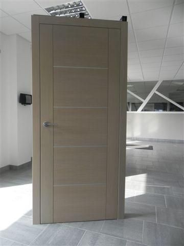 Une porte intérieure fermée, de couleur brun clair, avec une poignée argentée, dans un espace de bureau moderne.