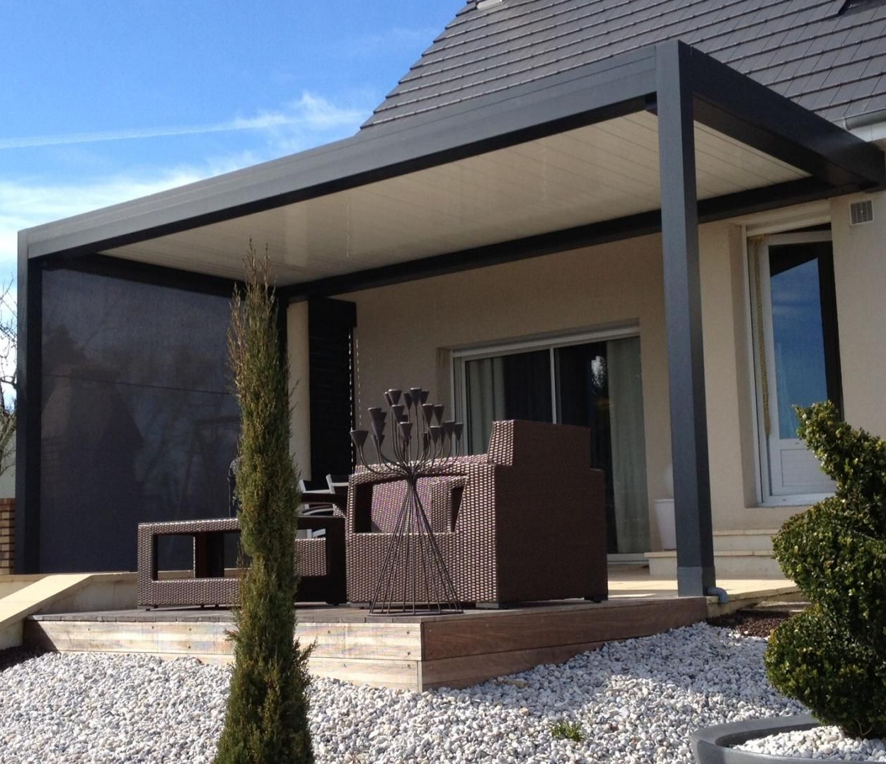 Pergola moderne gris foncé, bardage beige, sièges et aménagement paysager.