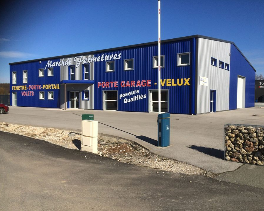 Bâtiment commercial bleu et gris avec signalétique pour les fenêtres, les portes et les portes de garage.