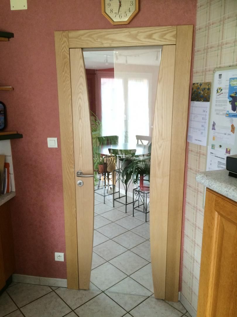 Cadre de porte en bois donnant sur une pièce avec une table et des chaises ; vue intérieure de la cuisine.