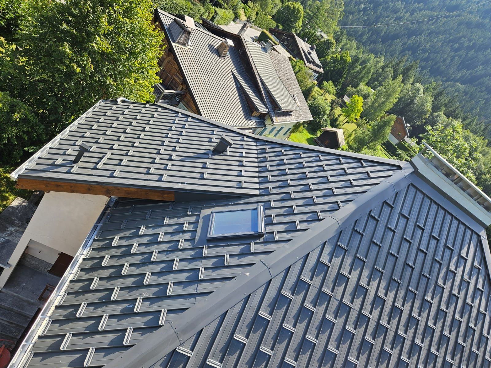 Maison au toit d'ardoise au milieu des arbres, vue d'en haut dans une région montagneuse