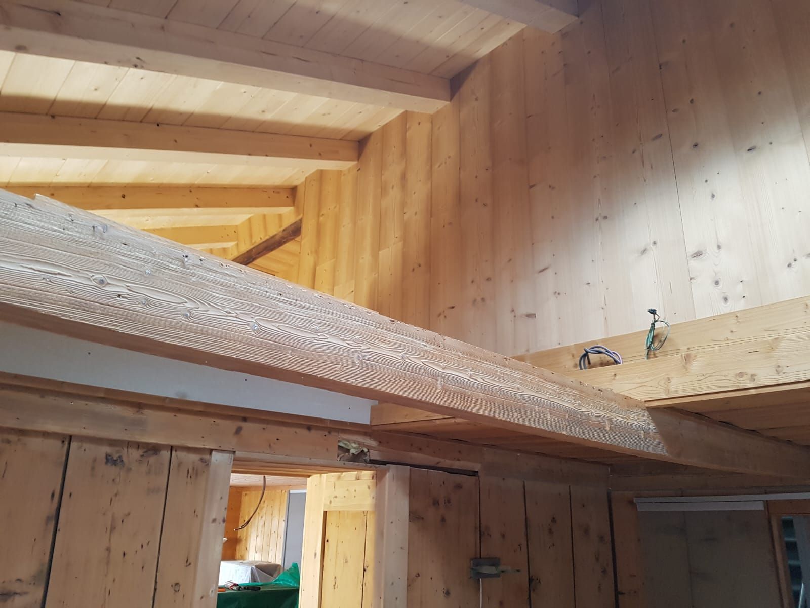 Intérieur d'une cabane en bois avec un lit mezzanine et une petite étagère en poutre exposant des figurines.