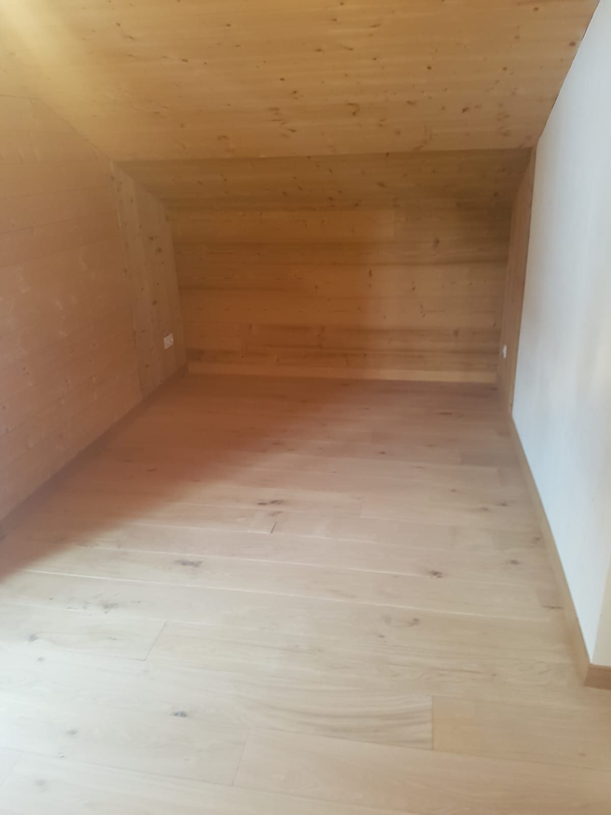 Pièce mansardée en bois vide avec plafond mansardé et parquet clair
