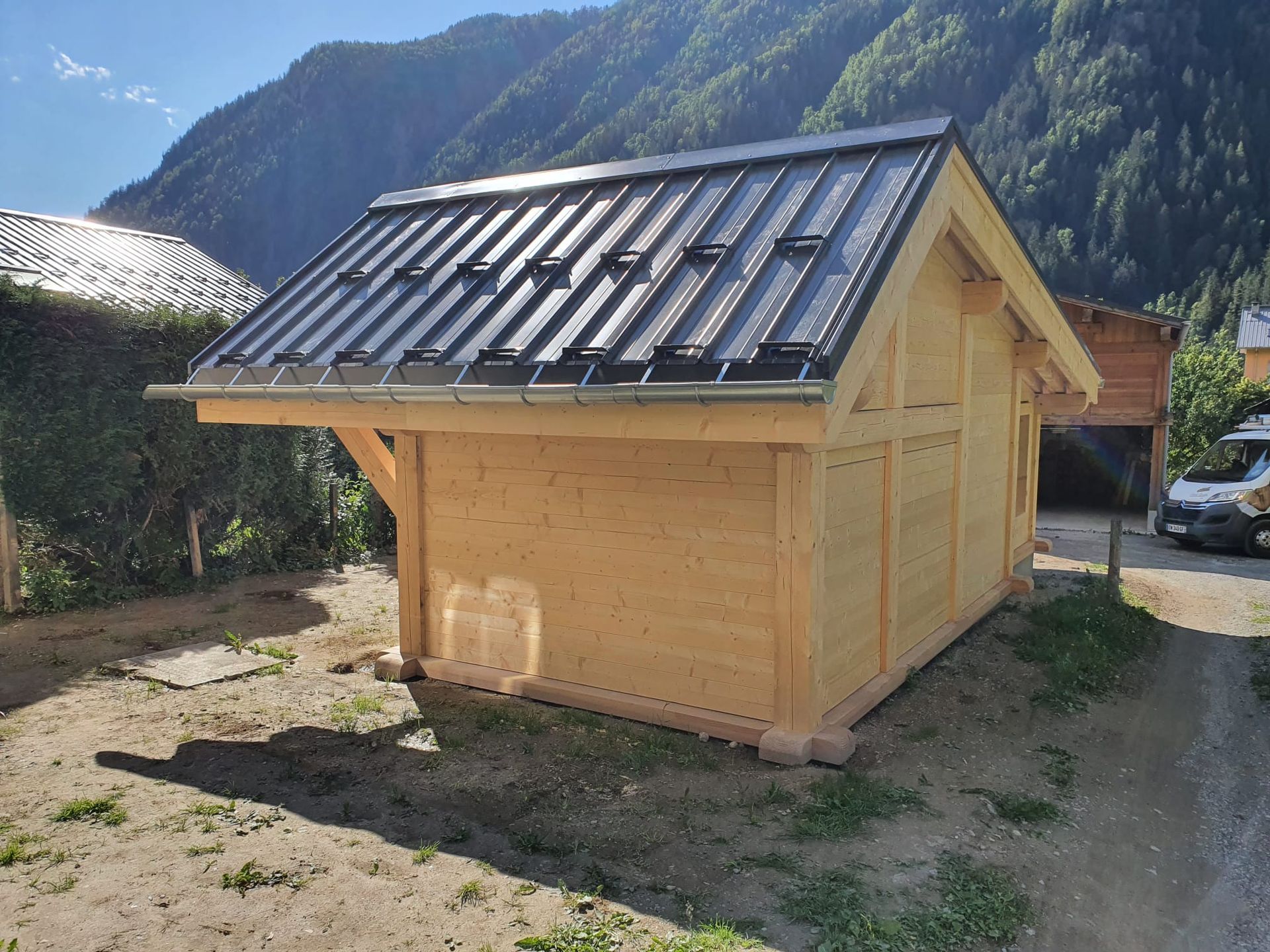 Petite cabane en bois avec un toit en métal sombre dans un cadre montagneux