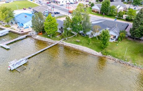 Aerial view of a waterfront property with docks, green trees, and buildings in a town setting.