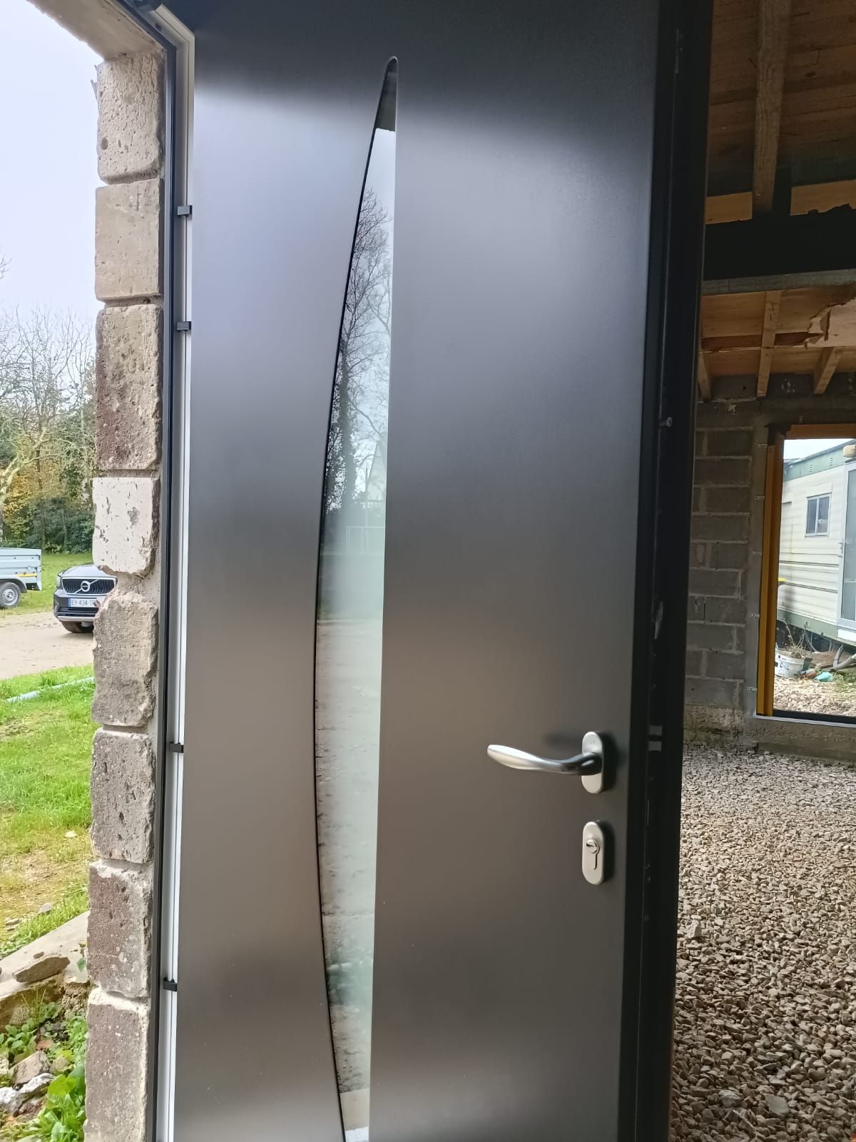 Porte d'entrée endommagée, présentant une longue fissure verticale et légèrement entrouverte.