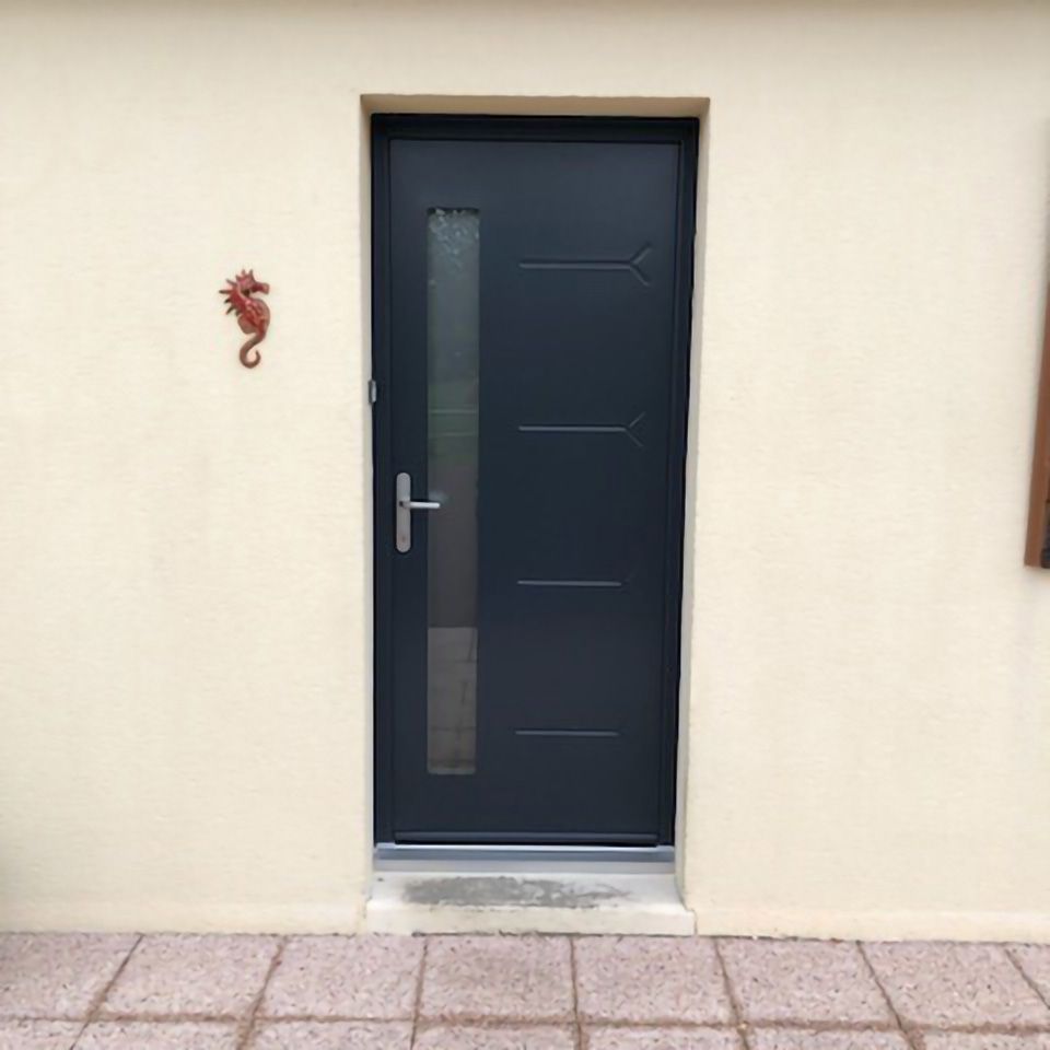 Porte d'entrée avec panneau gris foncé et fine bande de verre dans un mur extérieur couleur crème