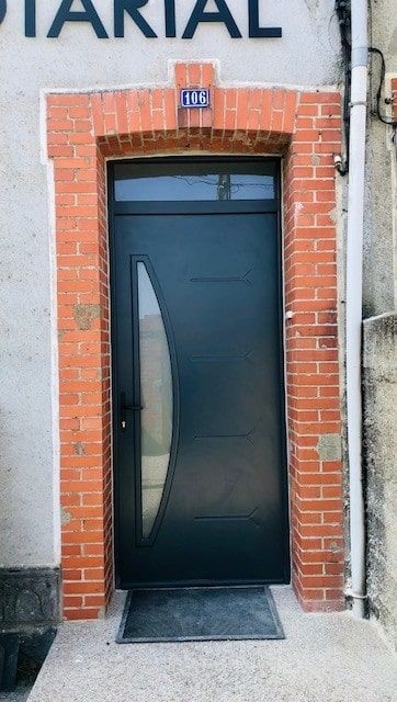Porte vitrée avec un cadre en briques rouges et une petite rampe à l'entrée