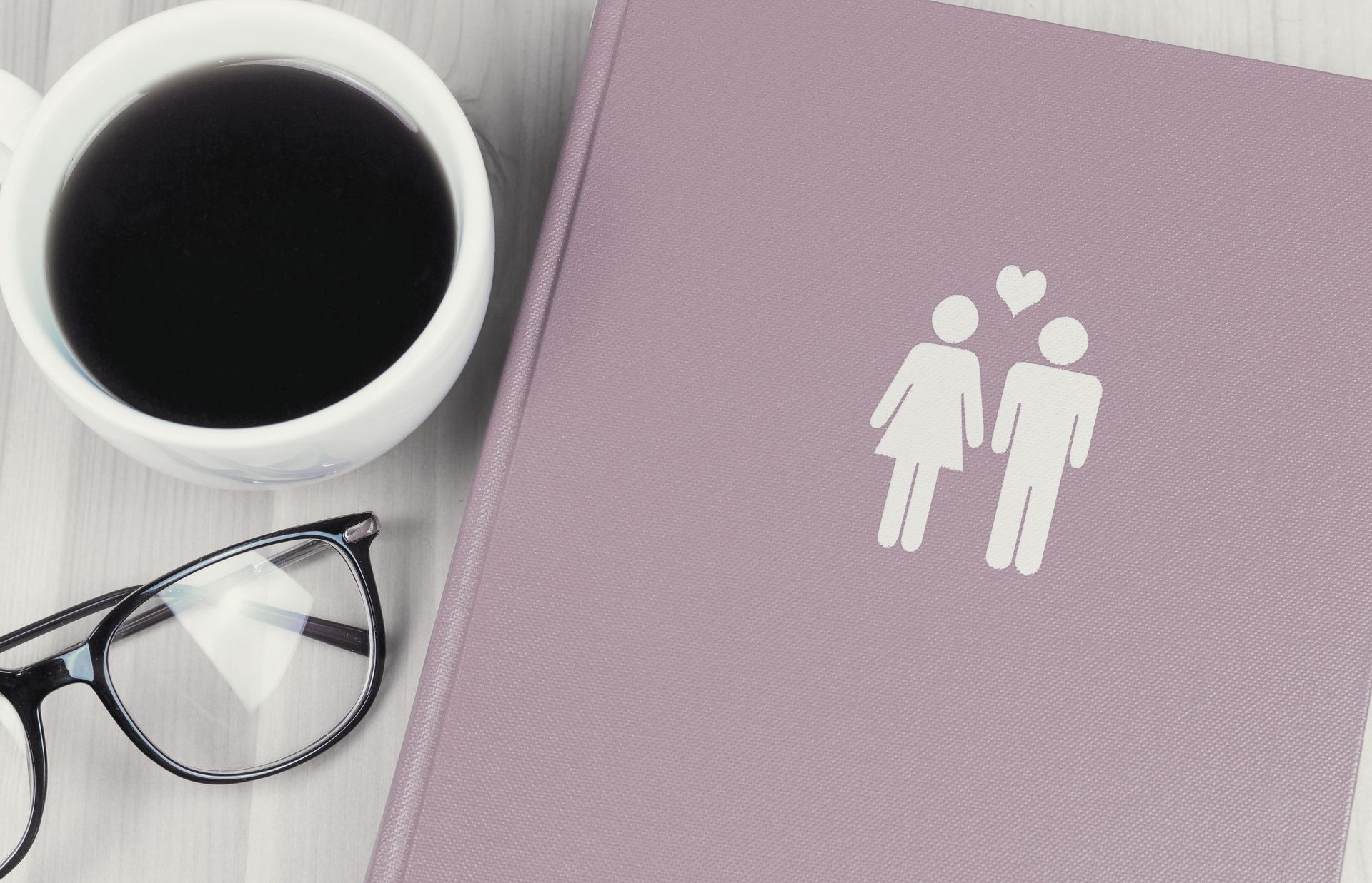 Tasse de café, paire de lunettes et carnet violet avec le pictogramme d'un couple - Sonia Bahouth psychologue, Cabinet Sagita