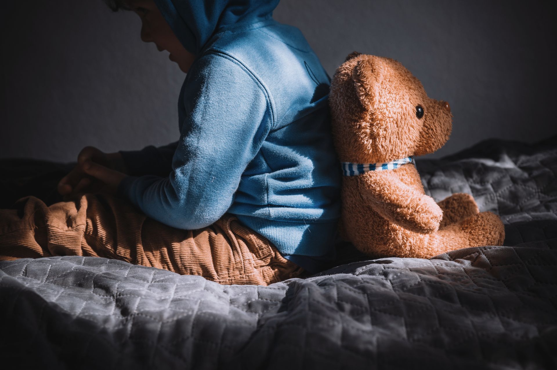 Un petit garçon triste assis dos à dos avec un ours en peluche - Sonia Bahouth psychologue, Cabinet Sagita