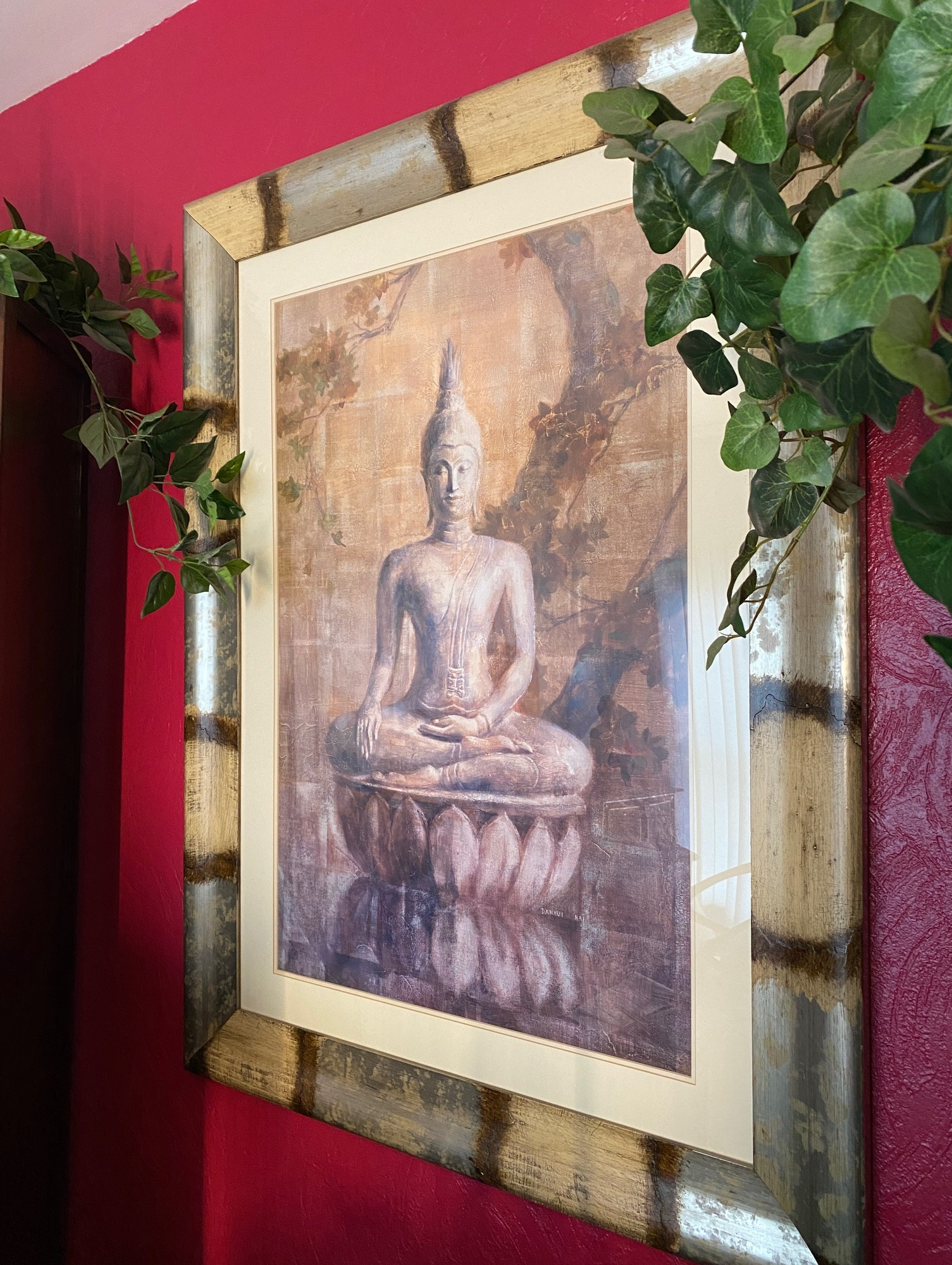 Tableau de Bouddha et plantes vertes sur un mur rouge - Cabinet Sagita à Dijon