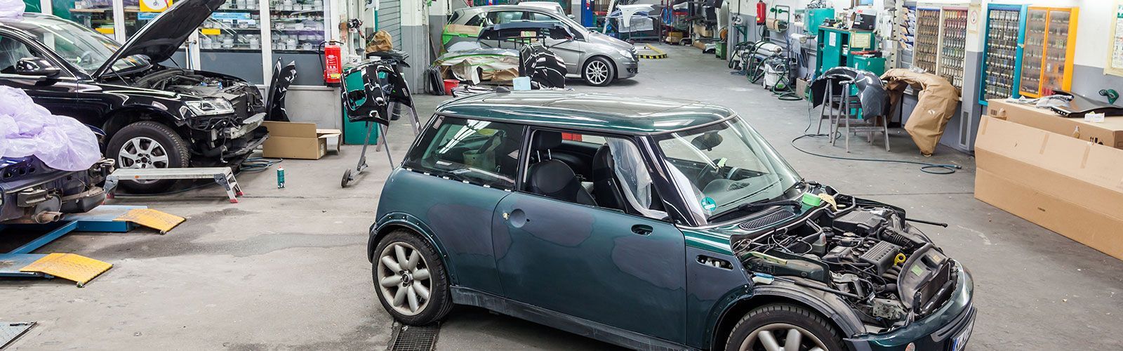 Ein Auto mit geöffneter Motorhaube steht in einer Garage.