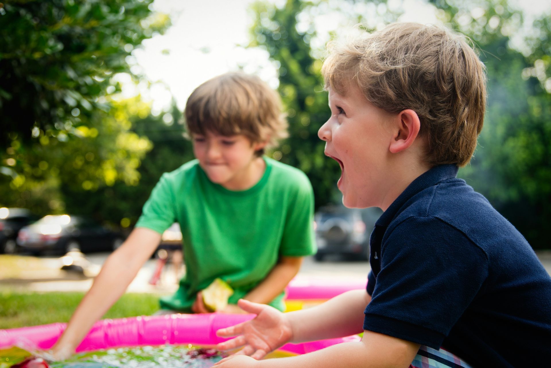 Two young boys are playing in an inflatable pool.