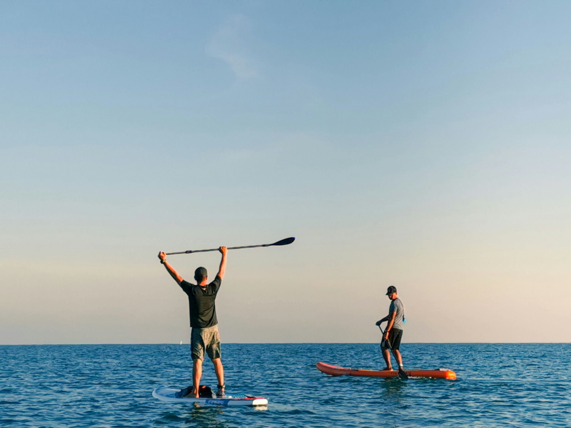 Two men are standing on paddle boards in the Chesapeake bay