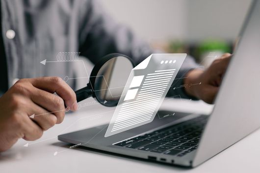 Un homme avec une loupe qui inspecte un document numérique