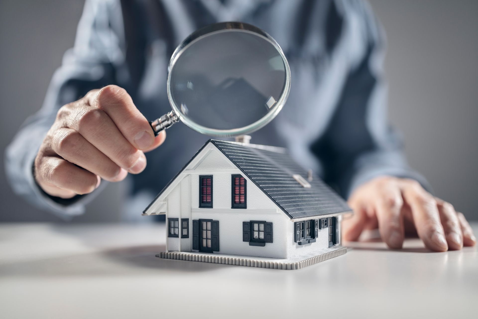 Quelqu'un tenant une loupe au dessus d'une maison