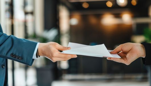 Une main tend un document vers une autre main