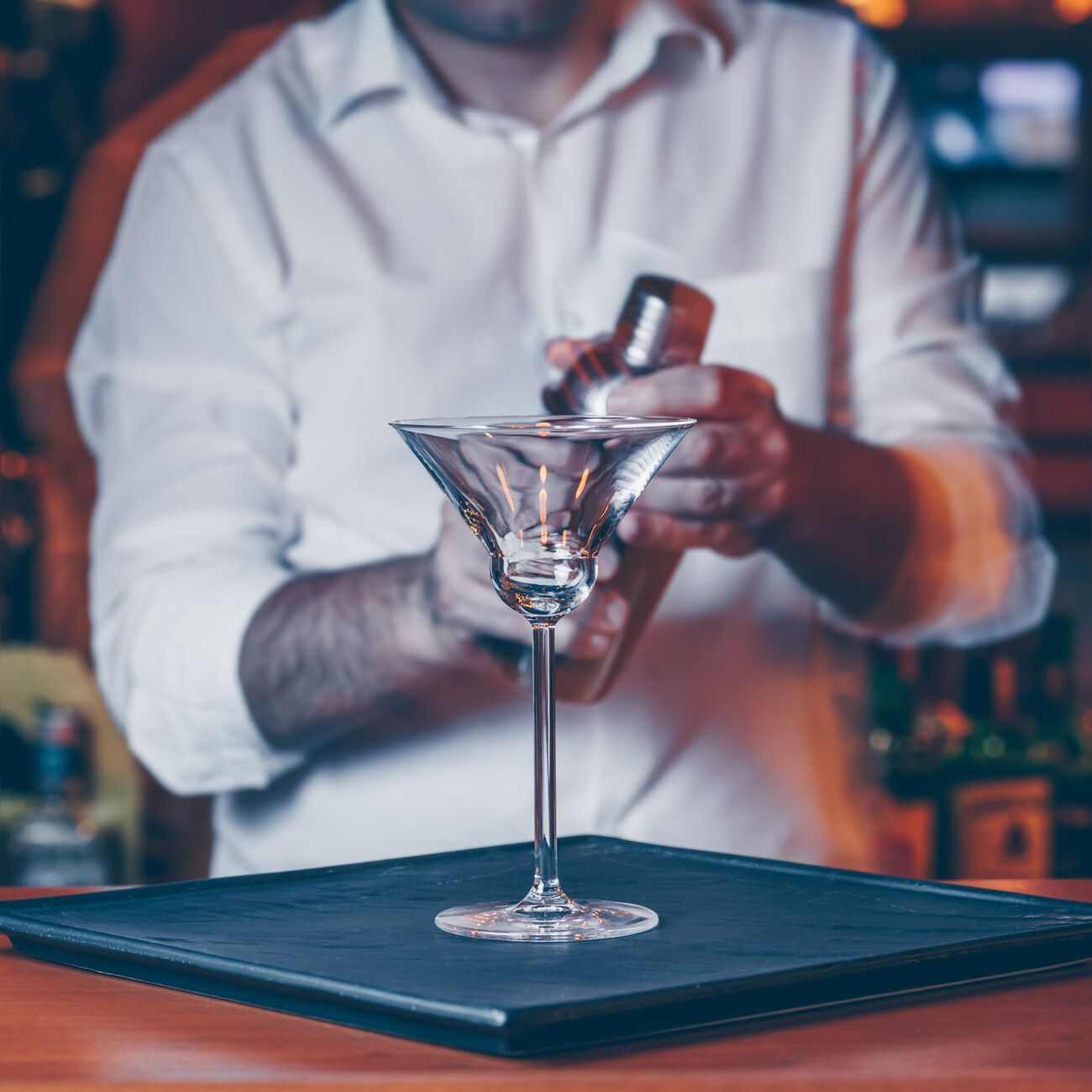 Un hombre con camisa blanca agita una copa de martini.
