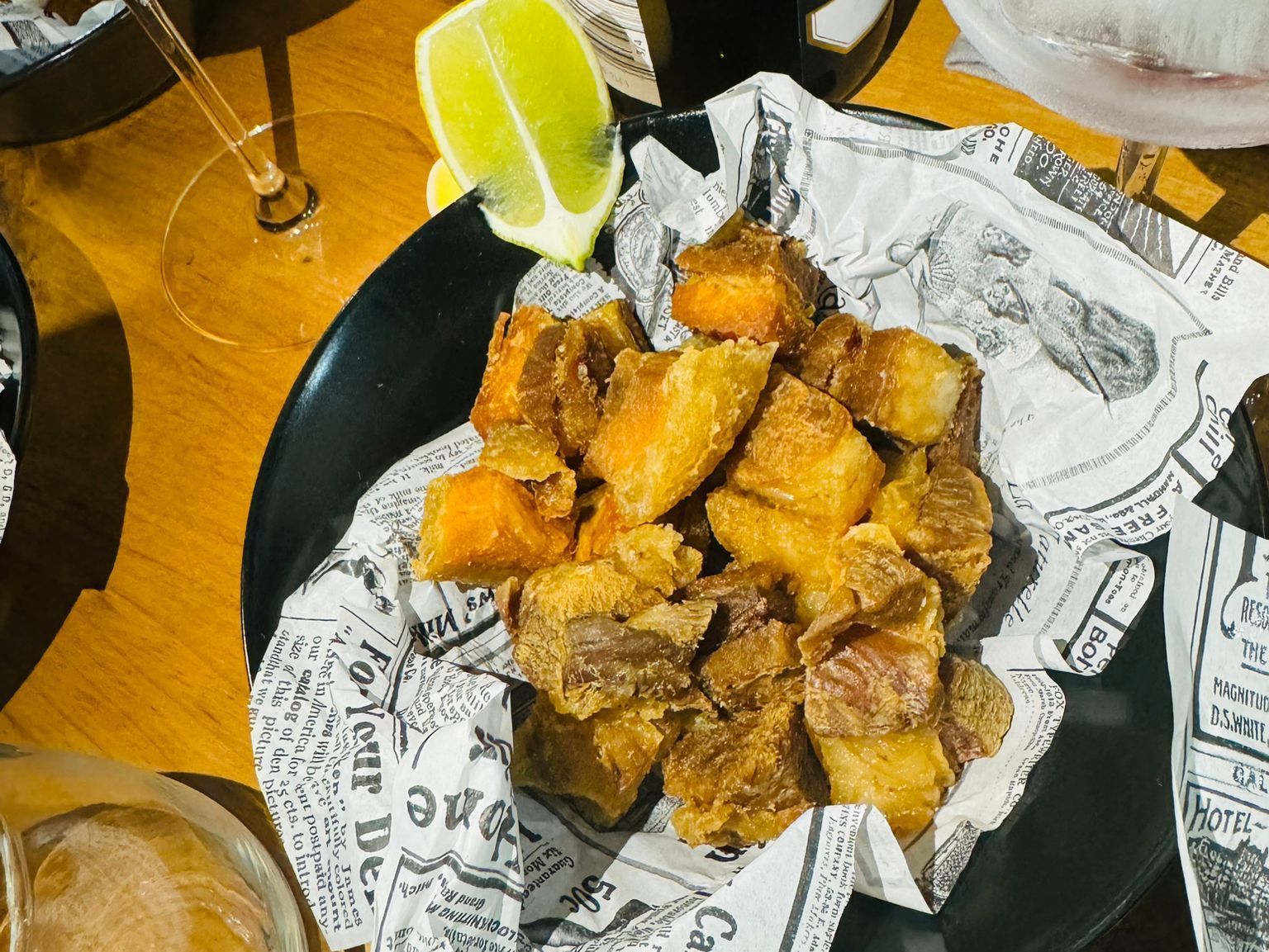 Un plato negro cubierto con comida frita y una rodaja de lima.