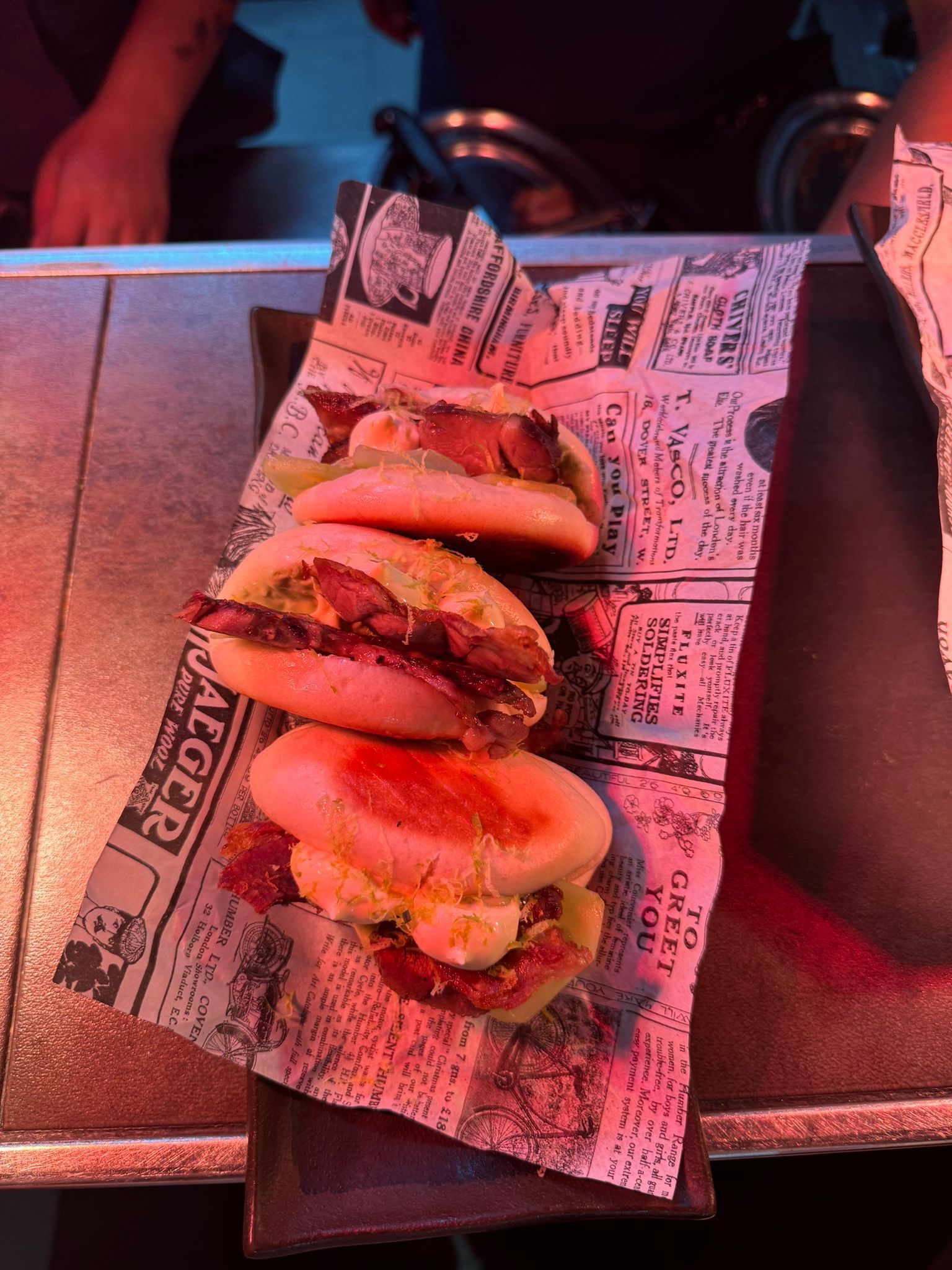 Un montón de sándwiches sobre papel de periódico sobre una mesa.