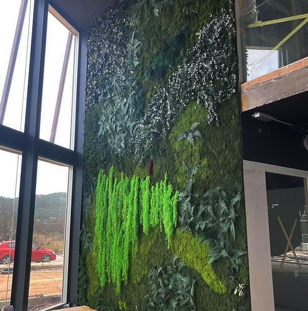 Eine grüne Wand mit vielen Pflanzen und Blättern darauf.