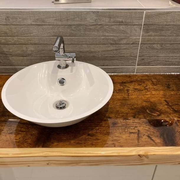 Auf einer Holztheke steht ein weißes Waschbecken.