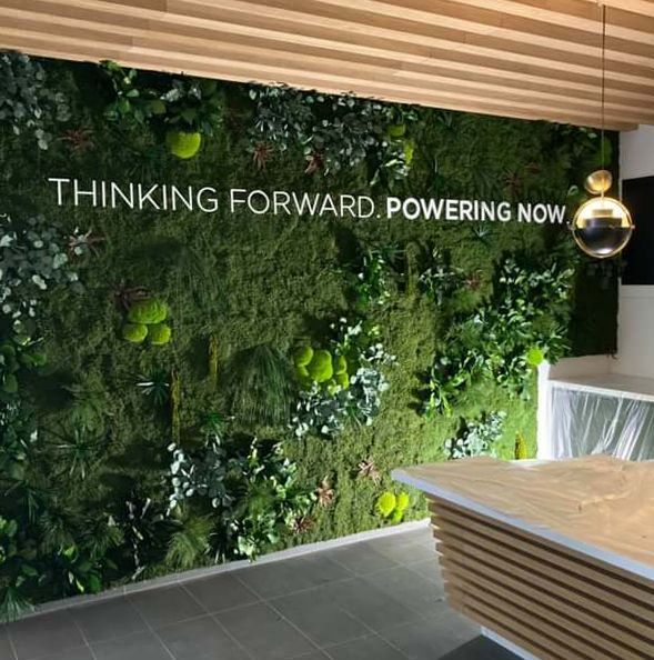 Eine grüne Wand mit einem Schild mit der Aufschrift „Thinking Forward Powering Now“