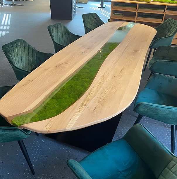 Ein Holztisch mit grünem Moos darauf und Stühle in einem Raum.