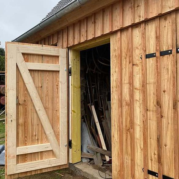 Ein Holzschuppen mit offenen Türen und einer gelben Verzierung.