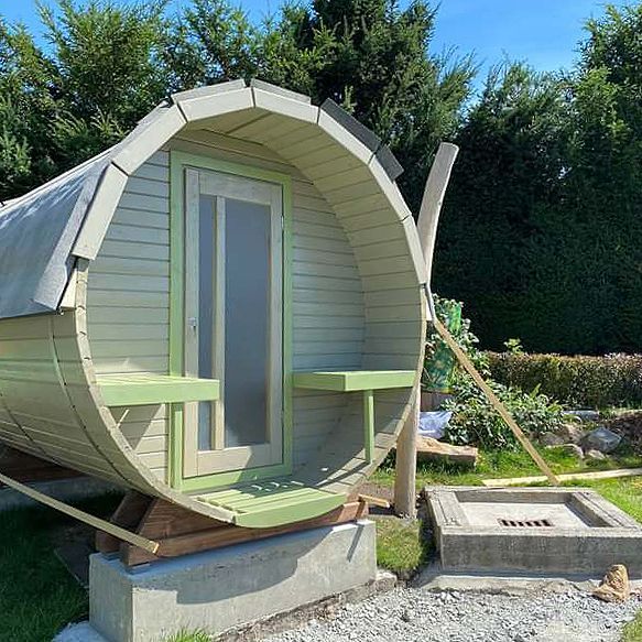 Ein Holzfass mit einem Tisch und Stühlen darin.