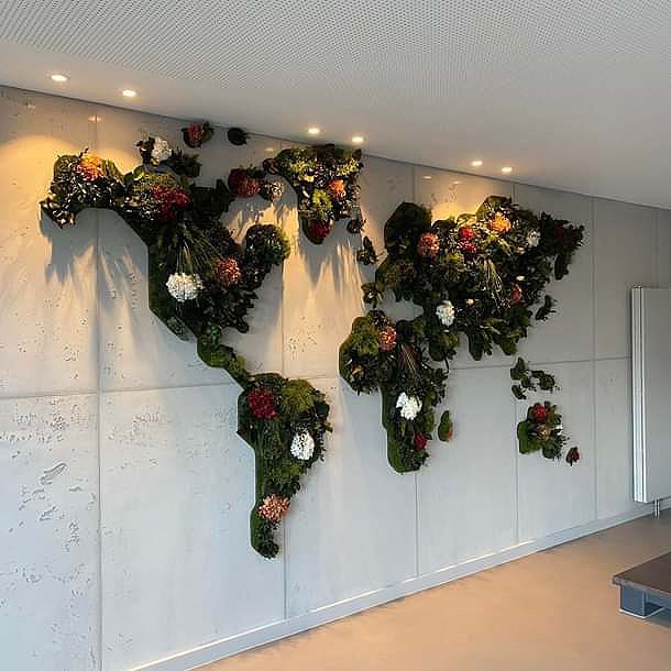 Eine Weltkarte aus Blumen und Moos an einer Wand.