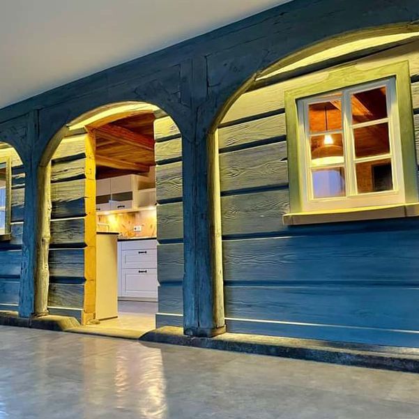 Ein blaues Holzhaus mit gewölbten Türen und Fenstern.