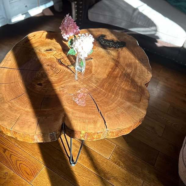 Ein Holztisch mit einer Vase mit Blumen darauf.