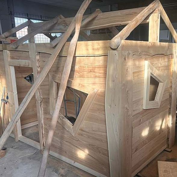 In einem Raum mit einer Leiter wird ein Holzspielhaus gebaut.