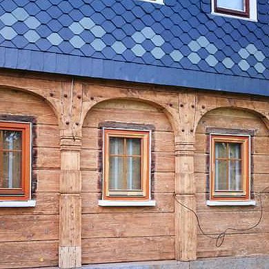 Ein Holzhaus mit Bogenfenstern und einem blauen Dach.