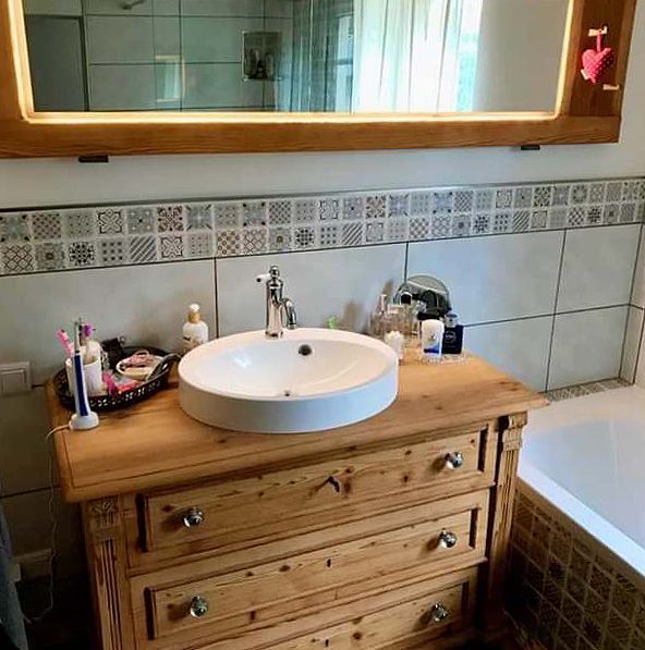 Ein Badezimmer mit Holzwaschtisch, Waschbecken, Spiegel und Badewanne.
