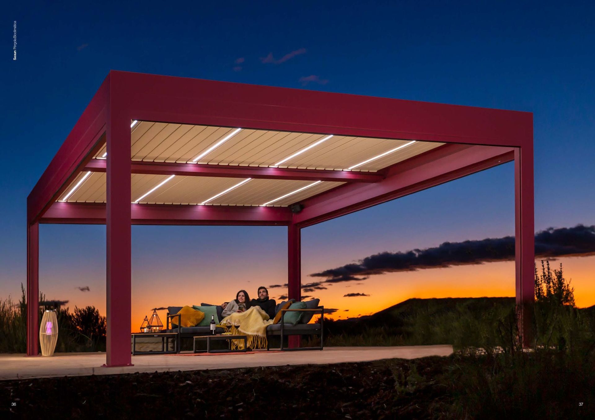 Dos personas están sentadas bajo una pérgola rosa por la noche.