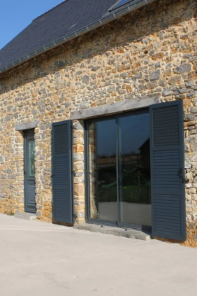 Maison en pierre avec des volets battants gris anthracite.