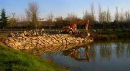 Una excavadora está trabajando en la orilla de un lago.
