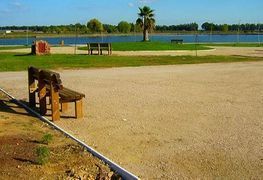 Un parque con un banco y un lago al fondo.